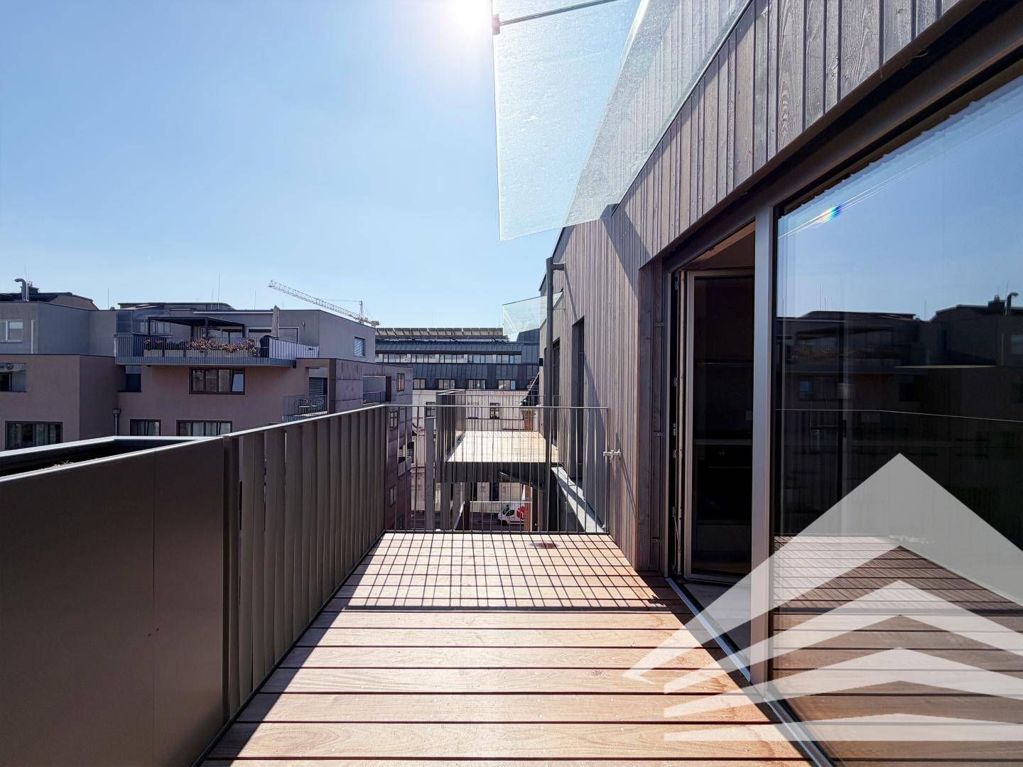 Sonniger Balkon mit Holzboden und schützender Glasüberdachung, ideal für entspannte Stunden im Freien.