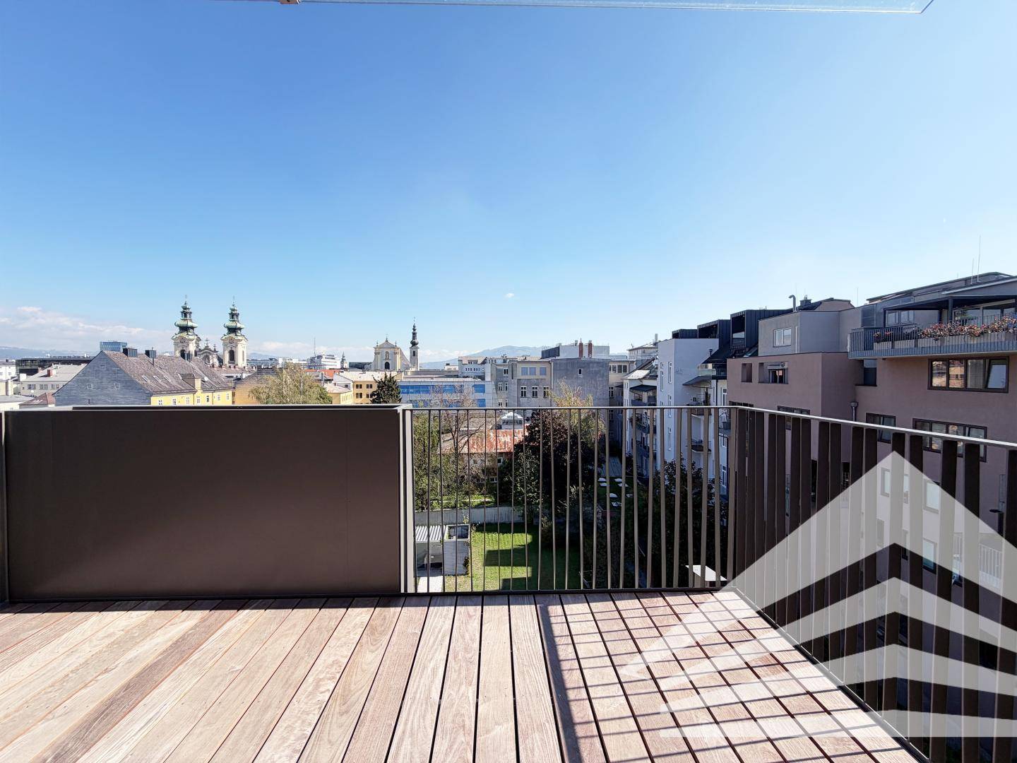Geräumiger Balkon mit Holzboden und moderner Metallbrüstung bietet einen weiten Stadtblick.