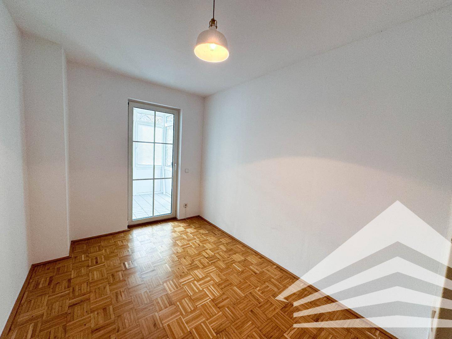 Schlafzimmer mit Parkettboden und direktem Zugang zum Wintergarten, bietet viel Tageslicht.