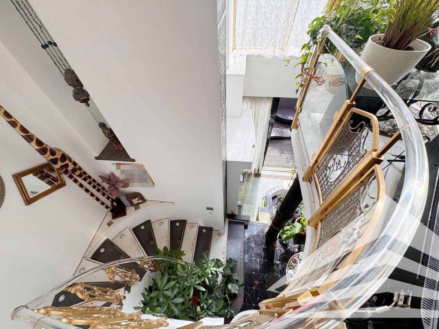 Elegante Wendeltreppe mit goldenen Akzenten und Blick auf die darunterliegende Etage.