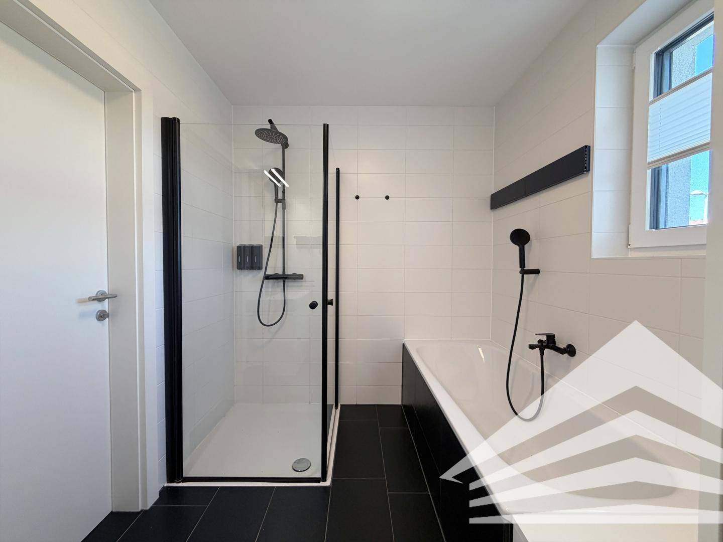 Modernes Badezimmer mit ebenerdiger Dusche, Badewanne und dunklen Bodenfliesen.