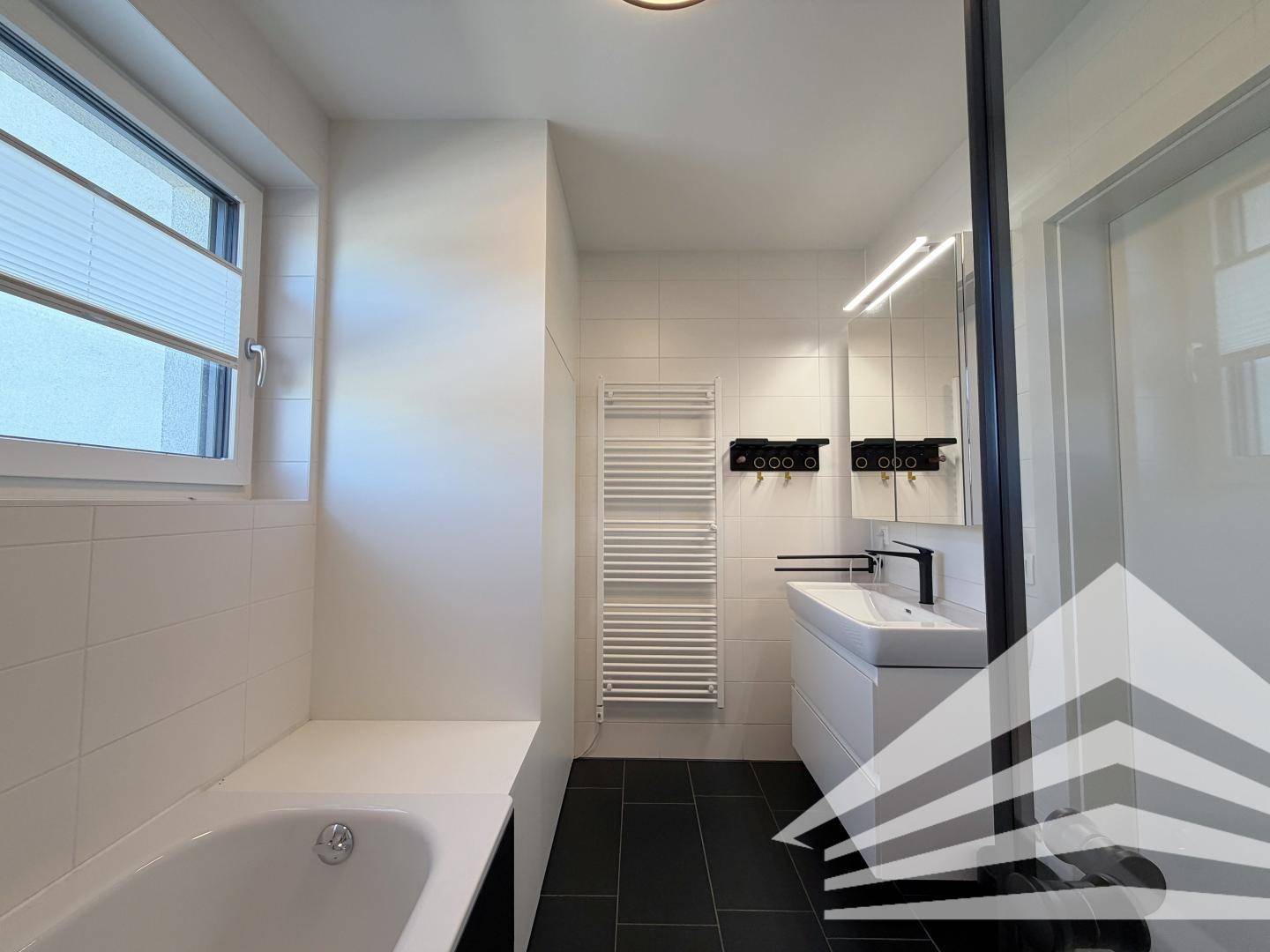 Modernes Badezimmer mit Waschtisch, Spiegelschrank und beheiztem Handtuchhalter.