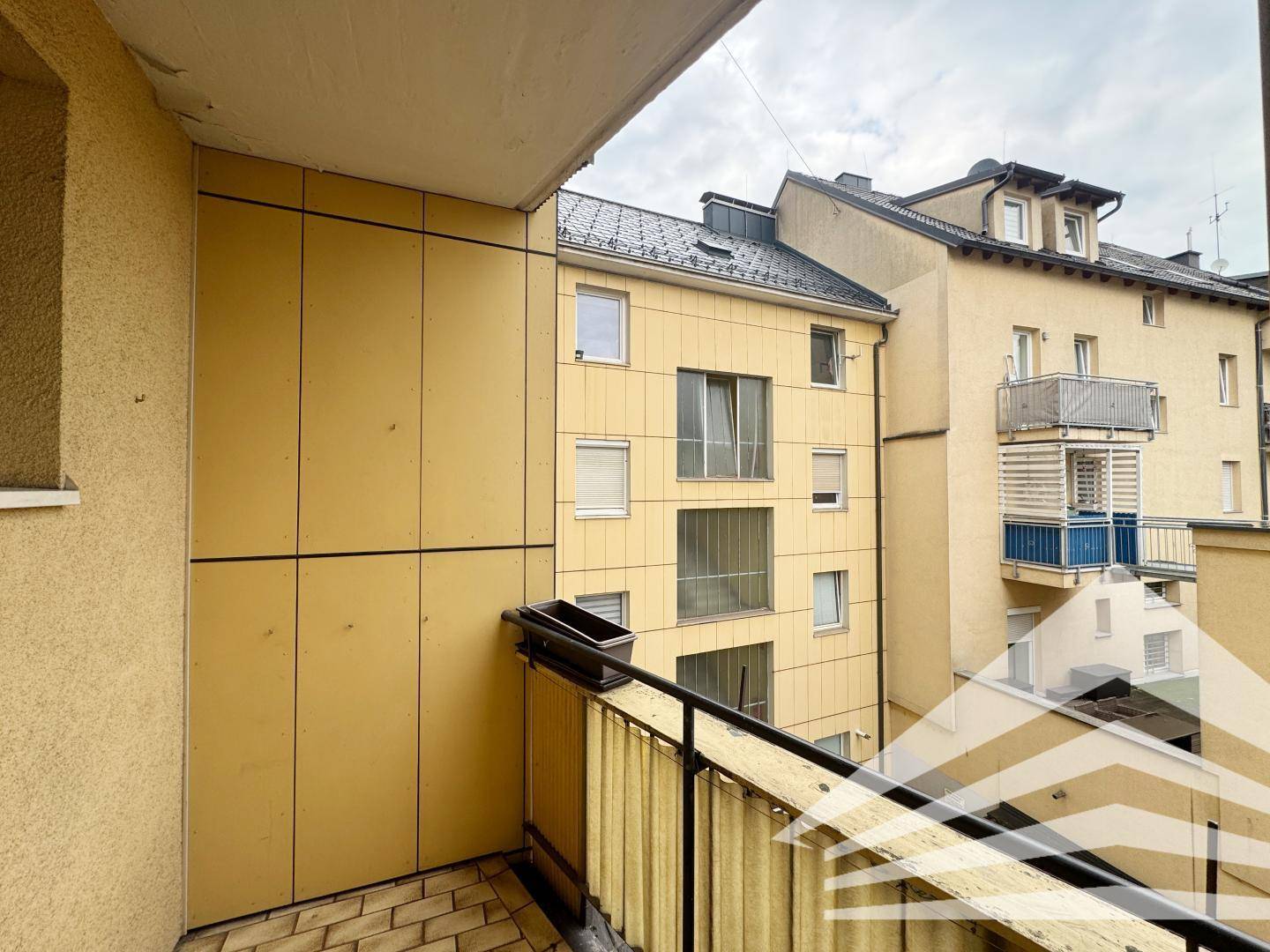 Balkon mit gelber Fassade und Blick auf die umliegenden Gebäude.