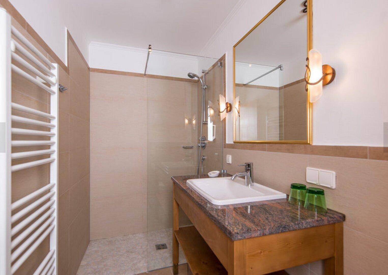Modernes Badezimmer mit begehbarer Dusche, Granitwaschtisch und Handtuchheizkörper.