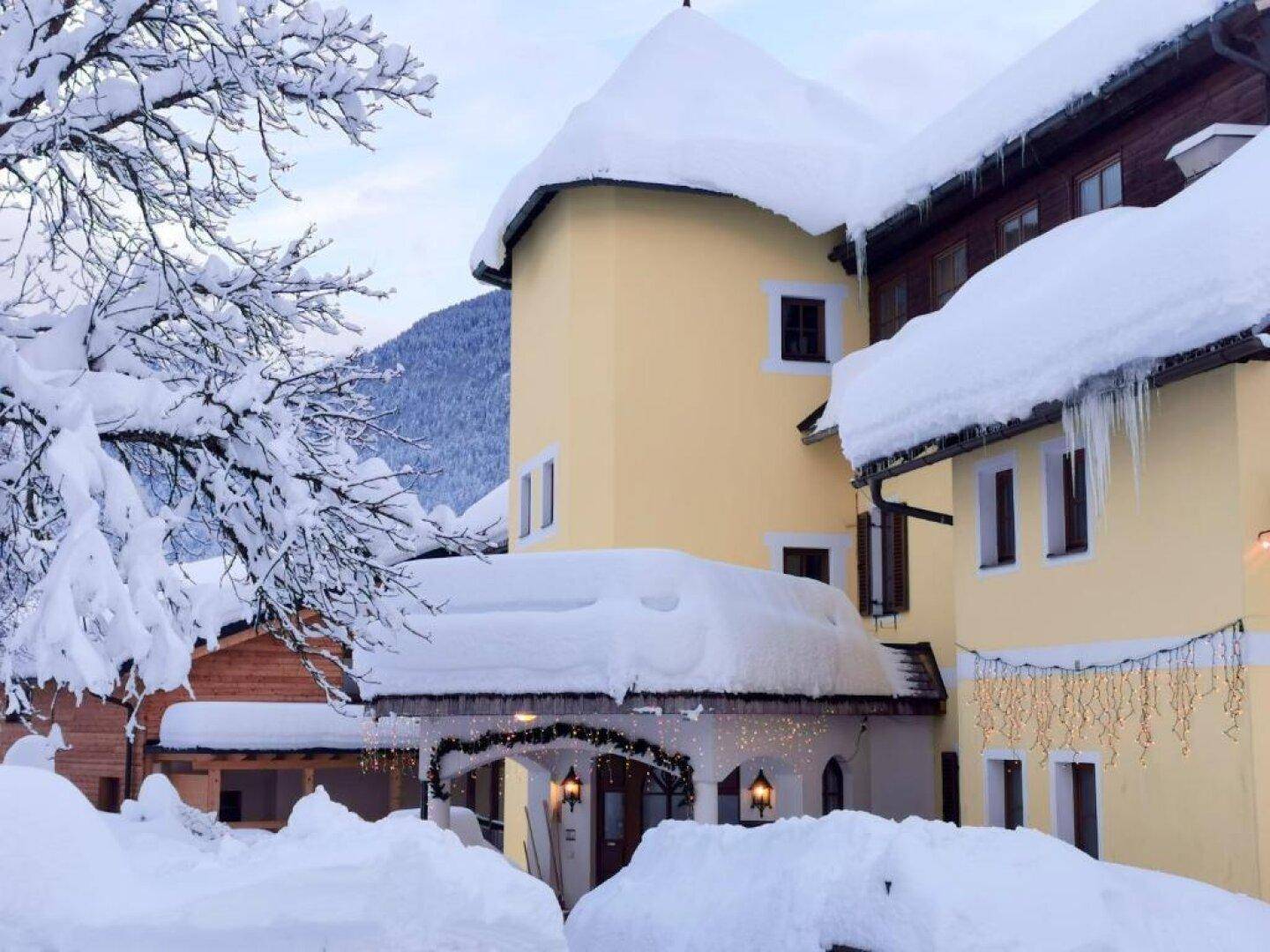 Detailansicht des Gebäudeeingangs im Winter, mit dicken Schneeschichten auf dem Dach und den umliegenden Flächen.