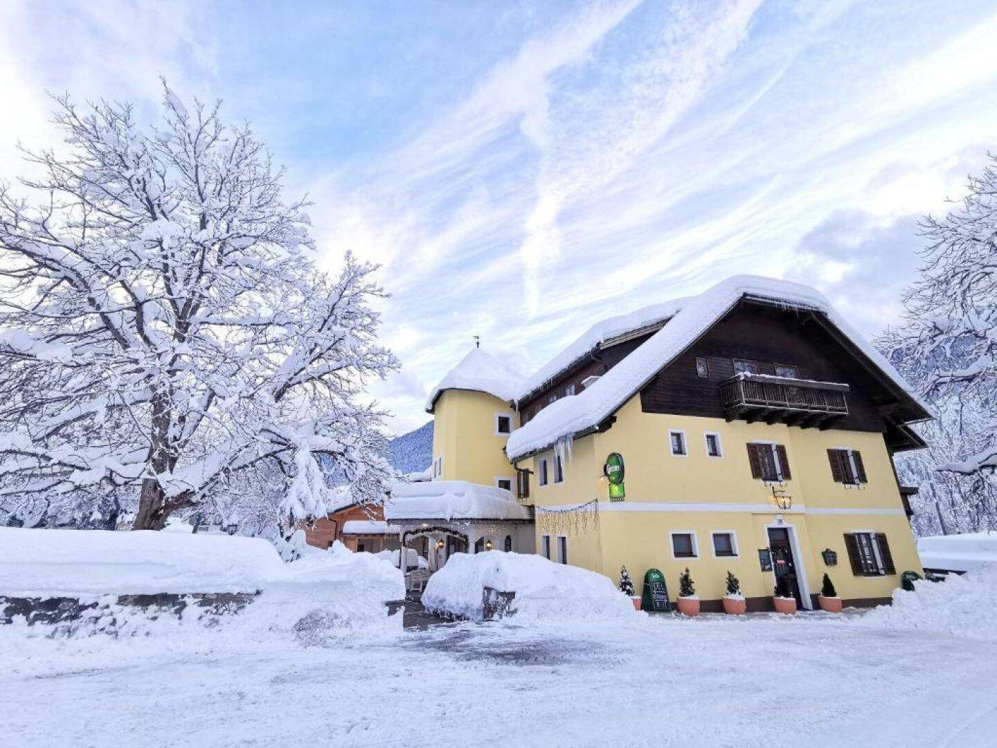 Malerisches Gebäude in winterlicher Landschaft, bedeckt mit Schnee und umgeben von verschneiten Bäumen.