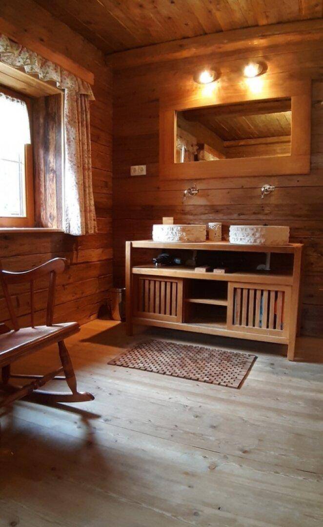 Rustikales Badezimmer mit Holzvertäfelung, Doppelwaschbecken und großem Holzspiegel.