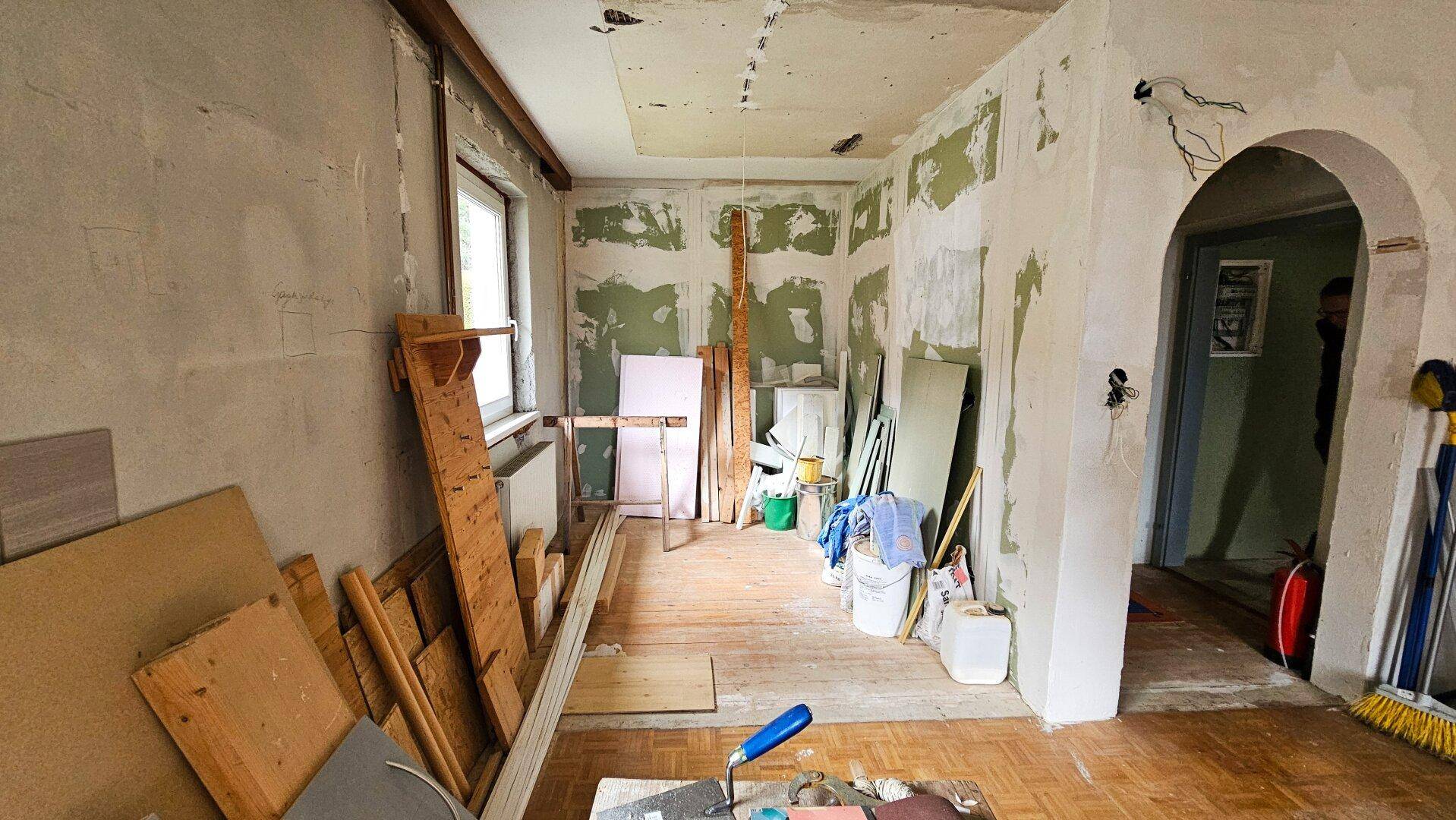 Innenraum in Renovierung mit freigelegten Wänden und Baumaterialien, bereit für den Ausbau.
