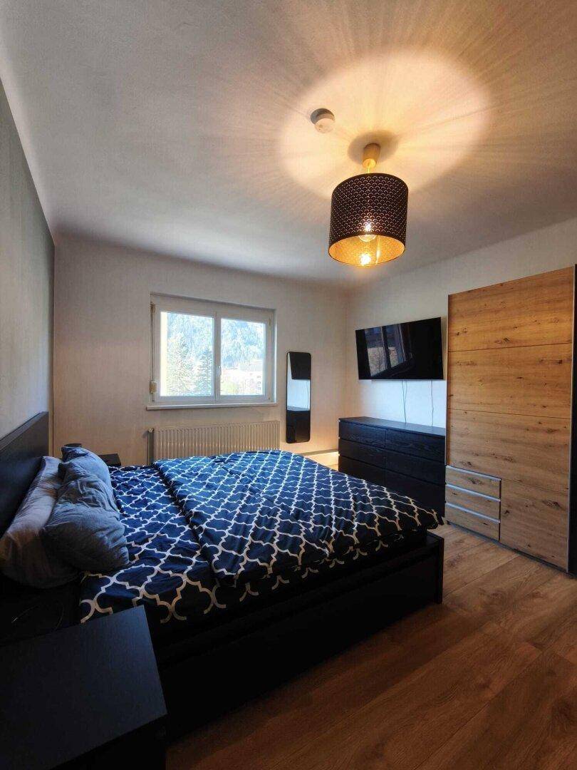 Gemütliches Schlafzimmer mit Doppelbett, Holzfußboden und Fenster mit Blick ins Grüne.