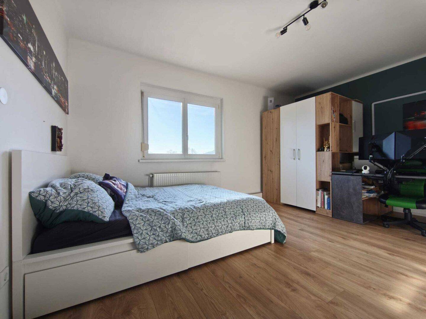 Helles Schlafzimmer mit Einzelbett, Schreibtisch und Schrank, ideal als Kinder- oder Gästezimmer.