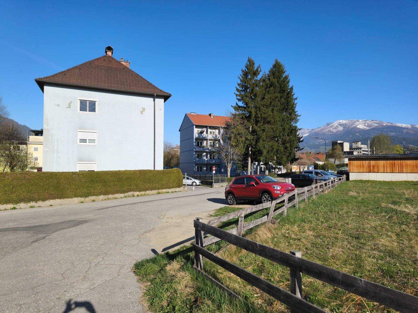 Außenansicht des Gebäudes mit Parkplätzen und Blick auf die umliegende Berglandschaft.