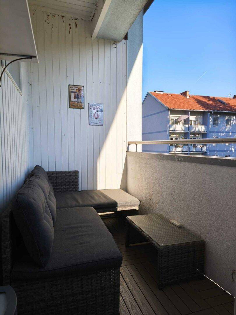 Sonniger Balkon mit bequemen Loungemöbeln und Blick auf die umliegenden Gebäude.