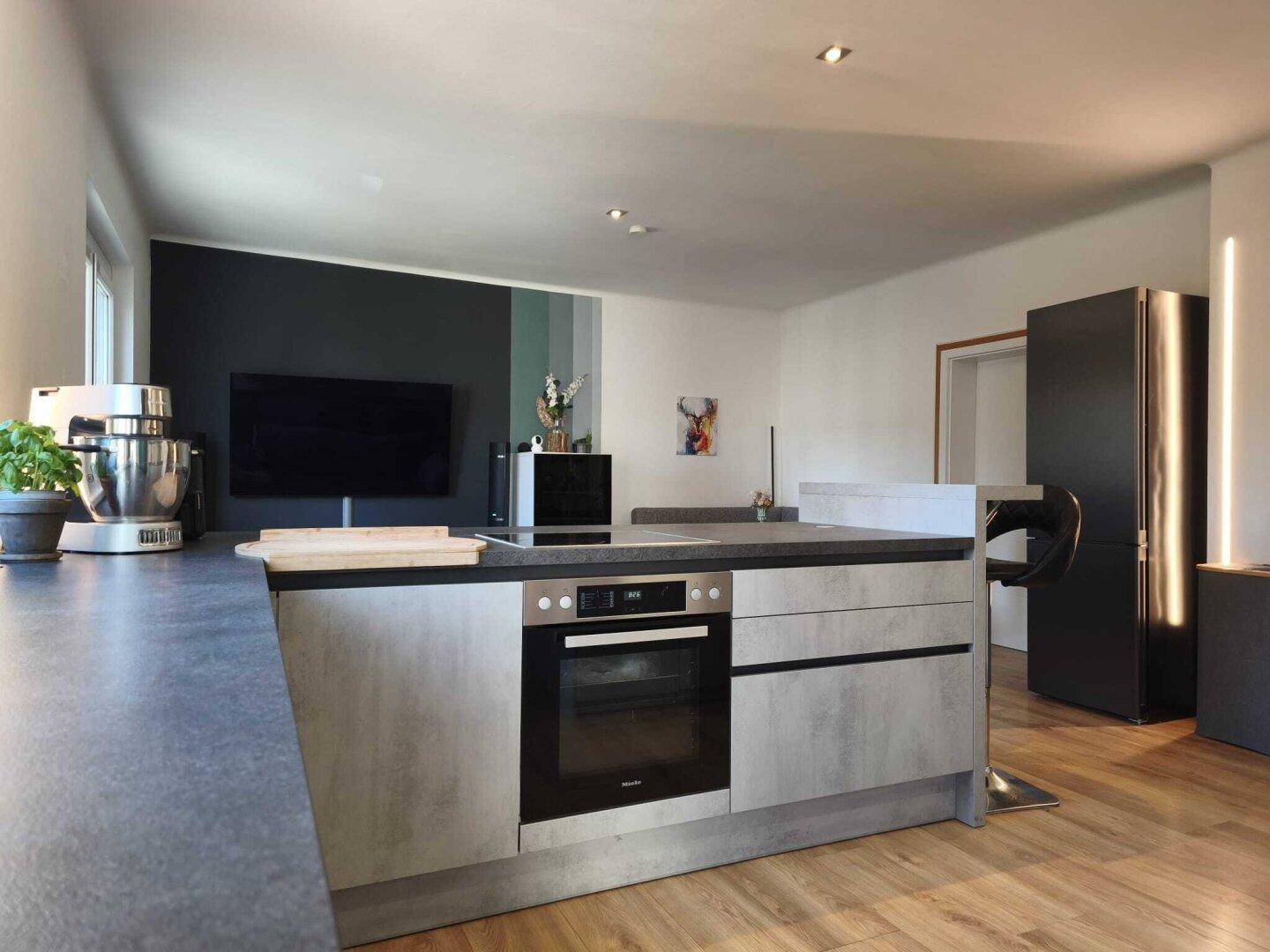 Moderne Kücheninsel mit integriertem Backofen und Kochfeld, ideal für geselliges Kochen.