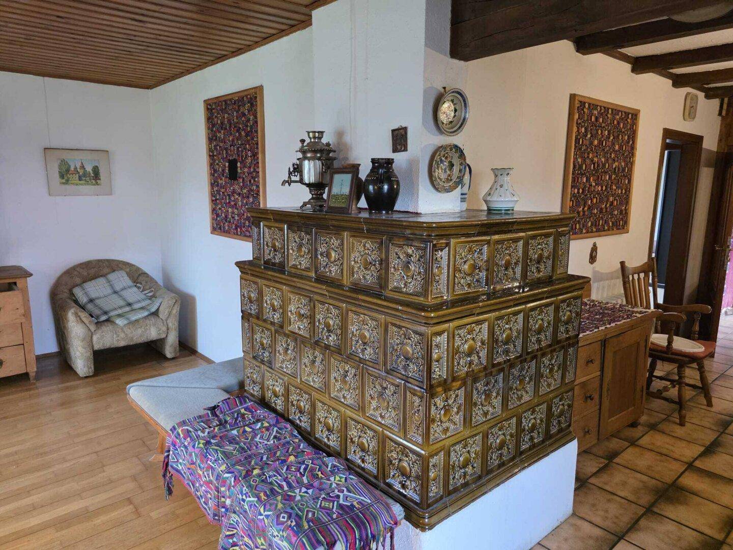 Gemütliches Wohnzimmer mit traditionellem Kachelofen, Holzbalkendecke und rustikalen Möbeln.
