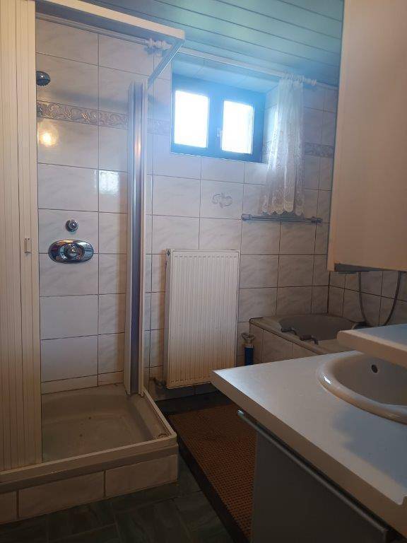 Badezimmer mit Duschkabine, Waschbecken und Fenster, in einem traditionellen Stil.