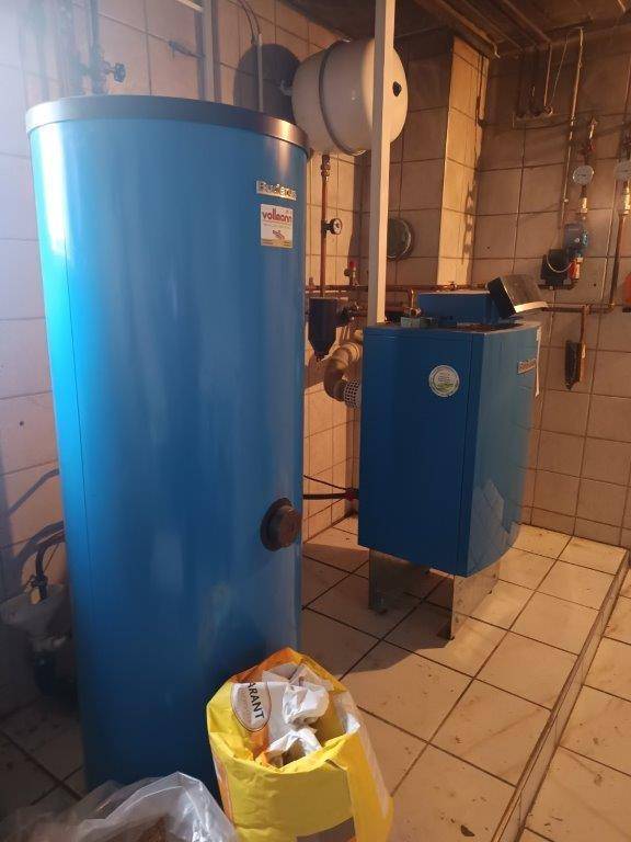 Heizungsraum mit großem Warmwasserspeicher und Heizkessel.
