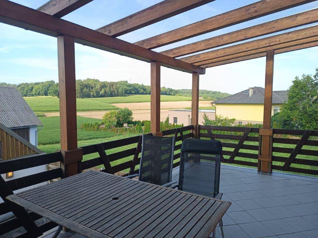 Geräumige Terrasse mit Holzpergola und Gartenmöbeln, bietet weiten Blick ins Grüne.