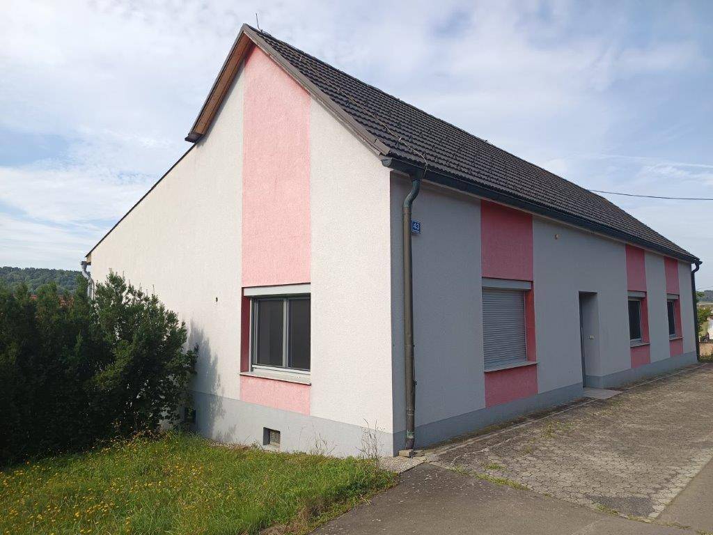 Vorderansicht des Wohnhauses mit farbiger Fassade und Fenstern mit Rollläden.