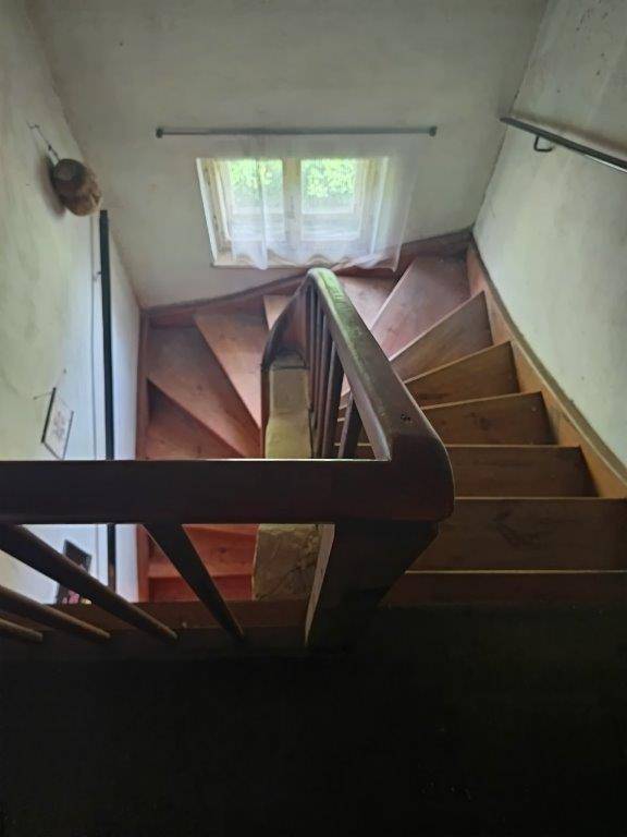 Holztreppe mit Geländer von oben gesehen, die zu einem oberen Stockwerk führt.