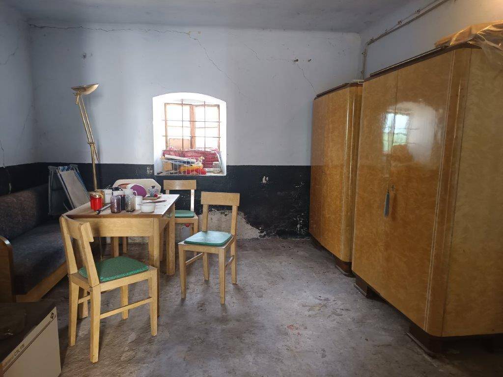 Rustikaler Raum mit kleinem Fenster, einfachen Möbeln und zwei großen Holzschränken, der Renovierung benötigt.