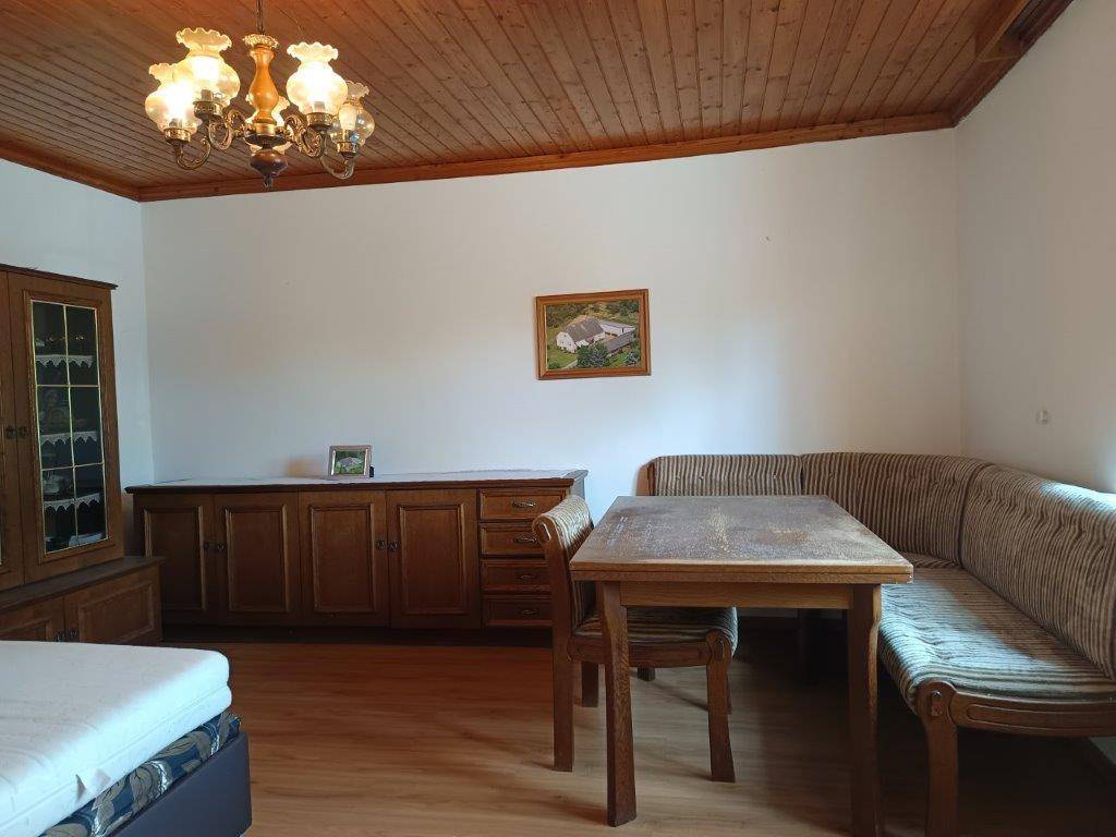 Schlafzimmer mit Holzdecke, Esstisch und Bank sowie einem großen Sideboard im traditionellen Stil.