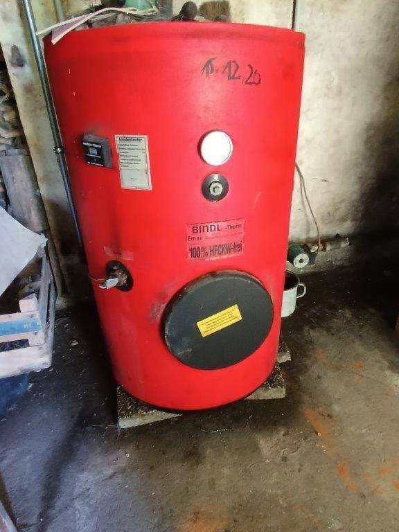Roter Warmwasserspeicher der Marke BINDL-Therm in einem einfachen Kellerraum mit Betonboden.