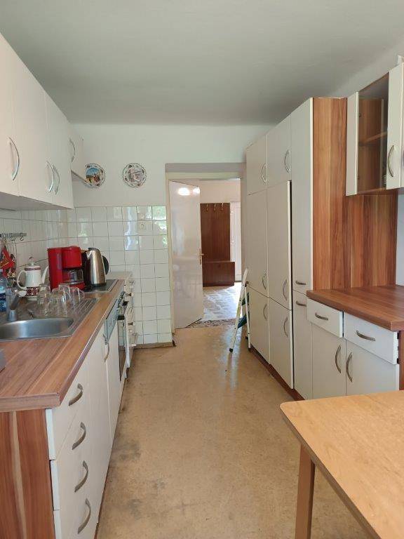 Funktionale Küche mit weißen Schränken, Holz-Arbeitsplatten und gefliesten Wänden im Landhausstil.