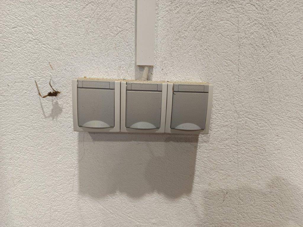 Drei Lichtschalter an einer weißen Wand, die die Beleuchtung im Raum steuern.