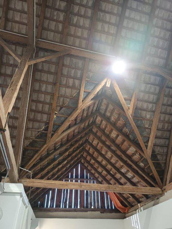 Dreieckige Dachkonstruktion aus Holz im Inneren der Scheune, die eine beeindruckende Raumhöhe schafft.