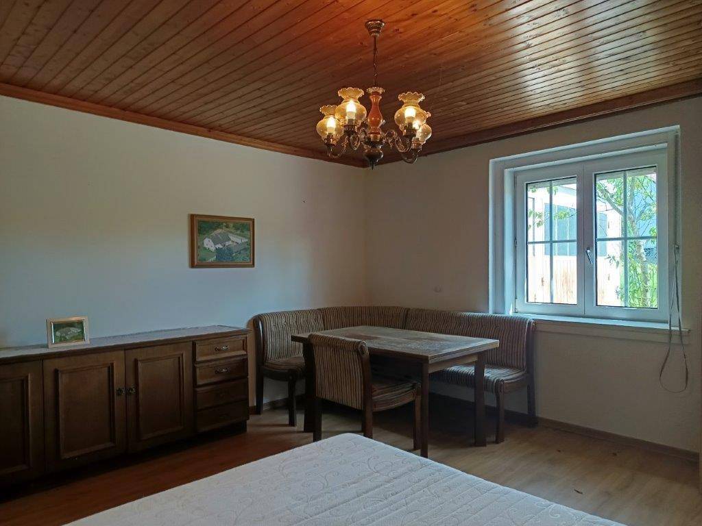 Helles Schlafzimmer mit Holzdecke, Esstisch und Fenster mit Blick ins Grüne, sehr einladend.