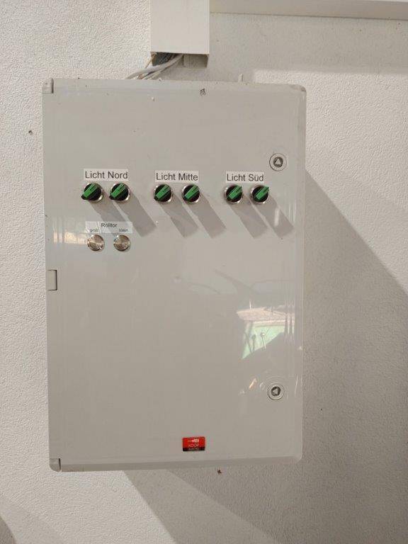 Elektrischer Schaltschrank mit Beschriftungen für Beleuchtung und Rolltorsteuerung.