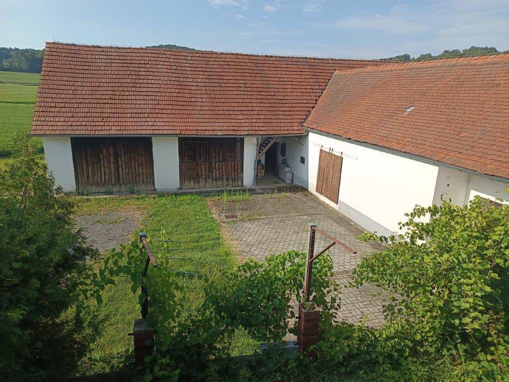 Innenhof mit gepflastertem Bereich und angrenzenden Scheunengebäuden unter blauem Himmel.