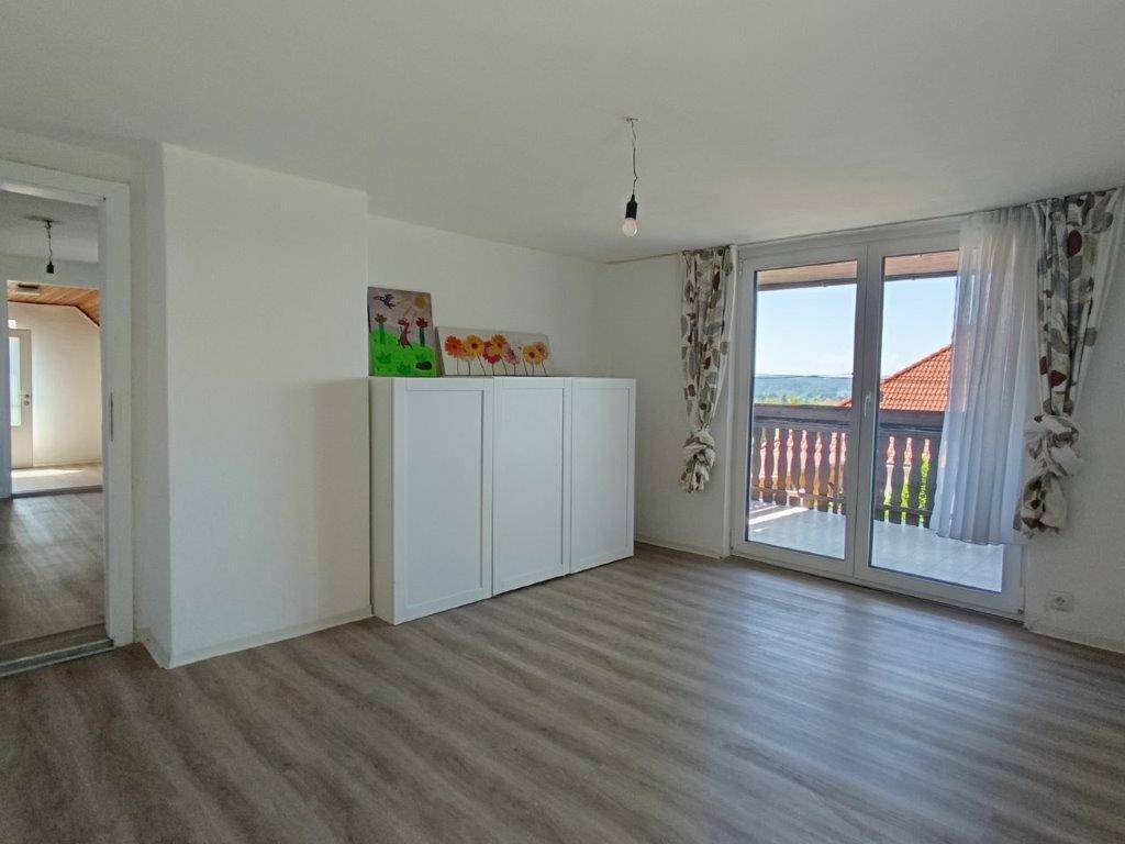 Helles Wohnzimmer mit Laminatboden und direktem Zugang zu einem Balkon mit Aussicht.
