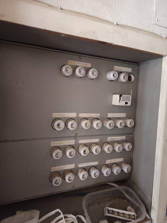 Alter Sicherungskasten mit vielen Keramik-Sicherungen, der auf eine ältere Elektroinstallation hinweist.