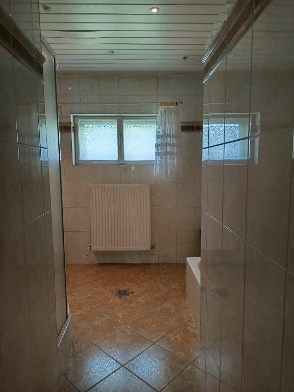 Gefliestes Badezimmer mit Fenster, Heizkörper und ausreichend Platz für weitere Ausstattung.