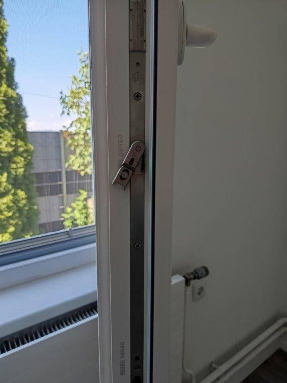 Detailansicht eines modernen Fensters mit Beschlag und Blick nach draußen.