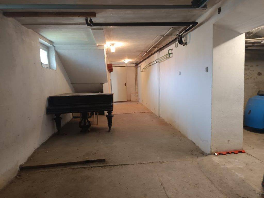 Heller Kellerraum mit Betonboden, Fenster und einem alten Klavier, bietet Stauraum.