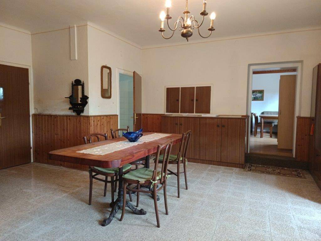 Traditioneller Essbereich mit Holztisch und Stühlen, umgeben von Holztäfelung und Fliesenboden.