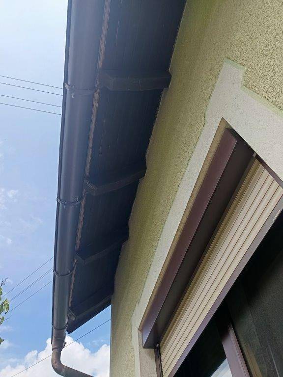 Detailansicht des Daches mit Regenrinne und der strukturierten Fassade des Hauses.
