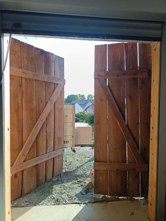 Offene Holztüren der Scheune geben den Blick auf die sonnige Außenwelt und die Nachbarschaft frei.