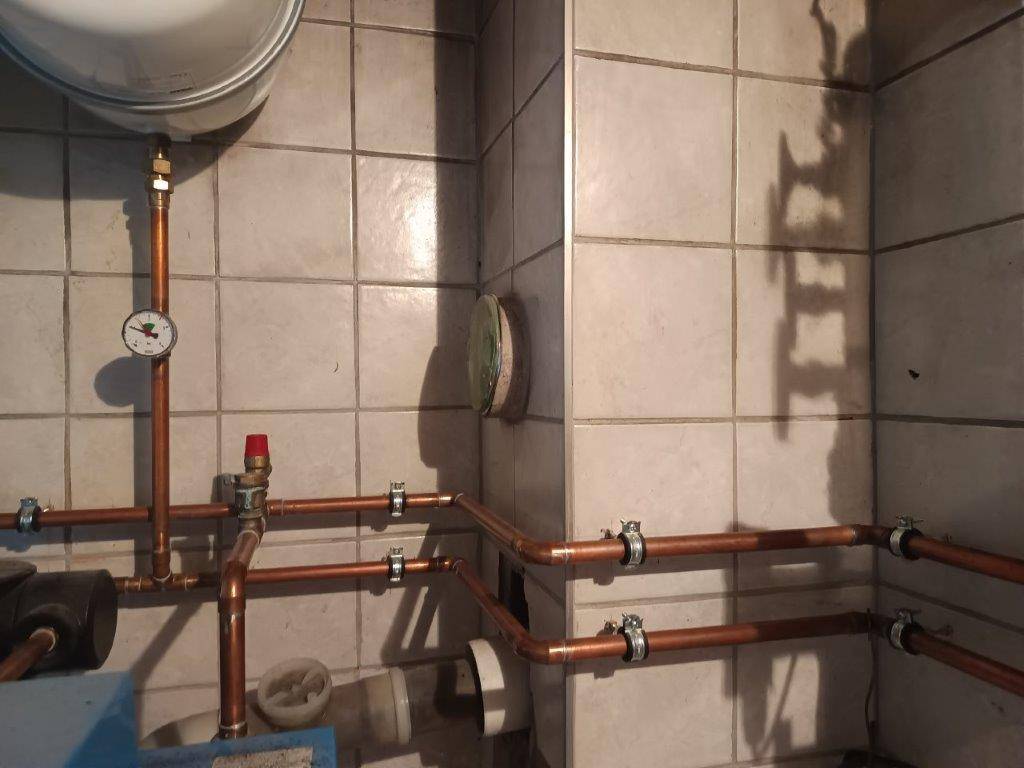 Detailansicht der Kupferrohrleitungen und Armaturen in einem Heizungsraum.