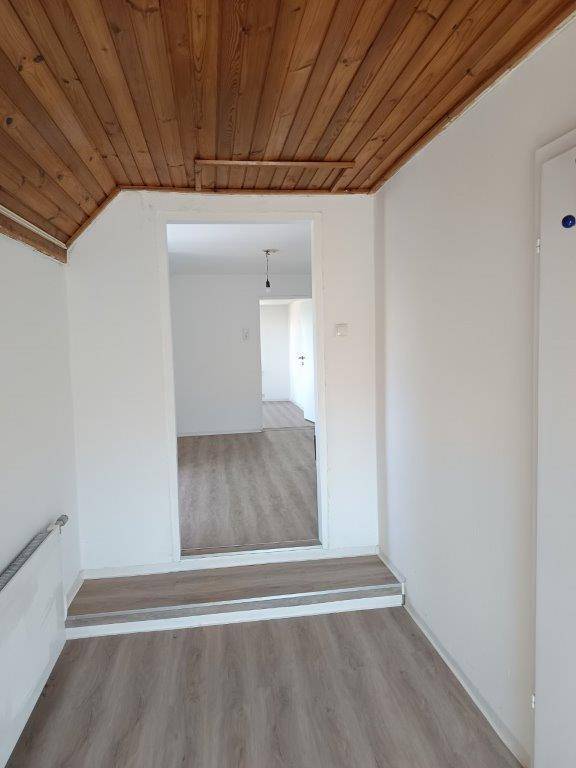 Flur mit Holzdecke, Laminatboden und Zugang zu weiteren Räumen im Dachgeschoss.