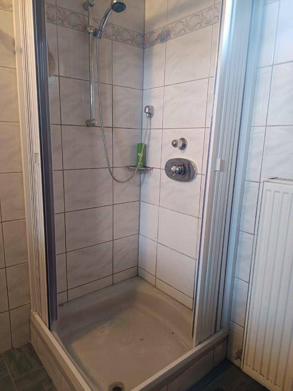Duschkabine mit weißen Fliesen und Duscharmatur in einem Badezimmer.