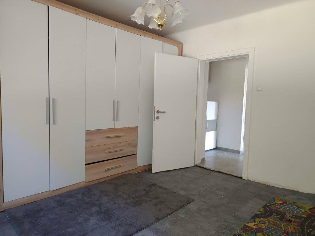Schlafzimmer mit großem Einbauschrank, Teppichboden und Zugang zu einem weiteren Raum.