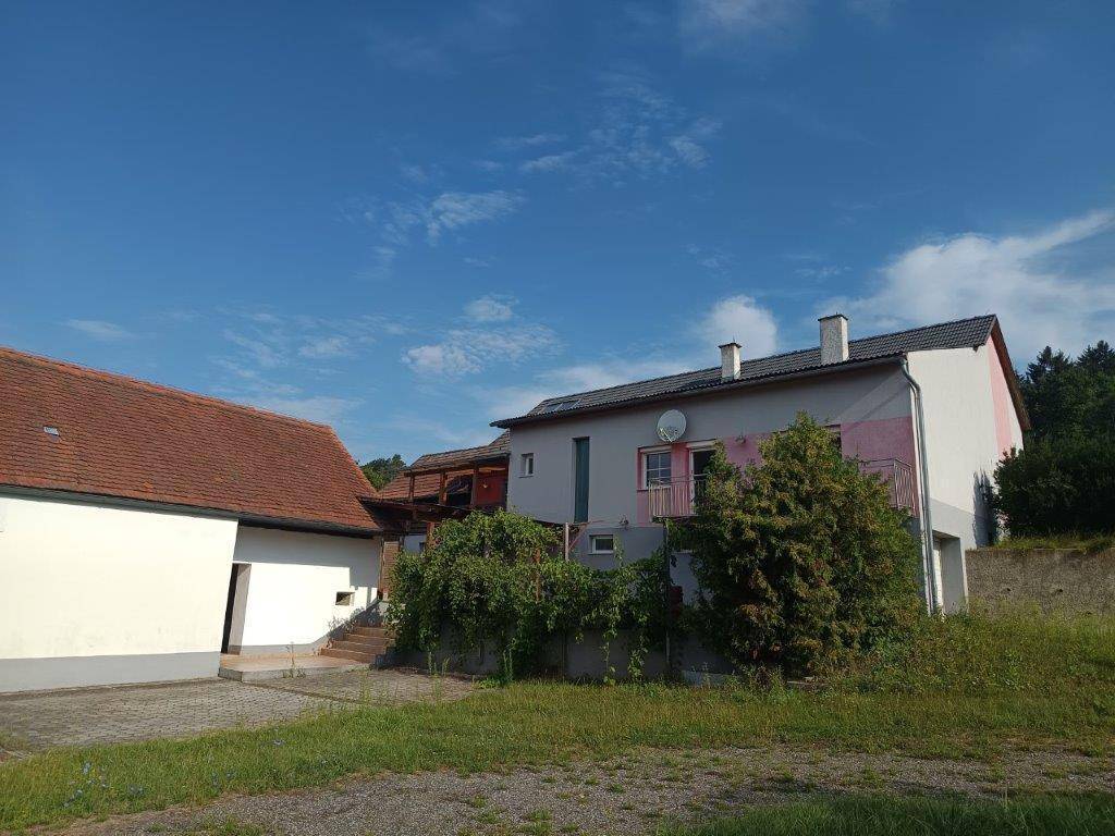 Wohnhaus mit farbiger Fassade und Balkon, umgeben von Bäumen und Grünflächen.