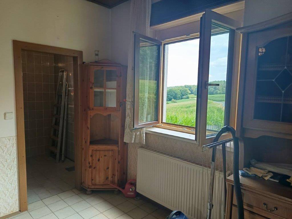 Heller Raum mit Fenster, Heizkörper und traditionellen Holzmöbeln, Blick ins Grüne.