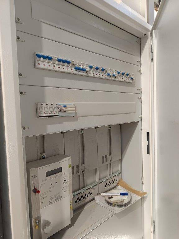 Offener Schaltkasten mit Sicherungen und Stromzähler, der die elektrische Installation zeigt.