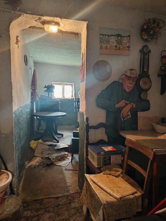 Kellerraum mit Durchgang zu einem weiteren Bereich und rustikaler Dekoration.
