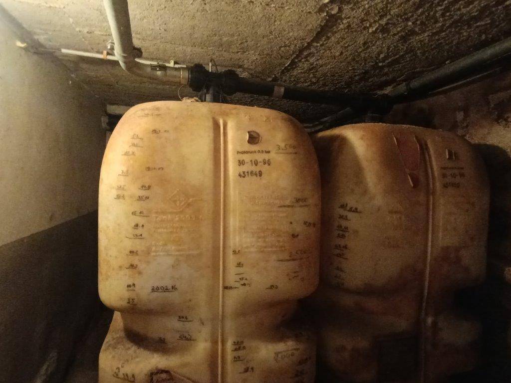 Zwei große Kunststofftanks, wahrscheinlich für Heizöl oder Wasser, in einem dunklen Technikraum.
