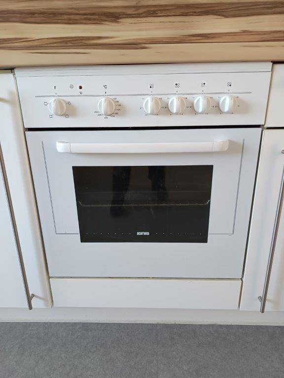Eingebauter Backofen mit Kochfeld und Bedienknöpfen in einer modernen Küche.